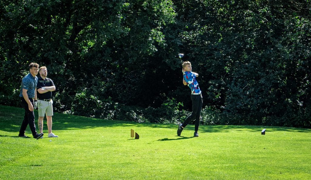 golfer hitting ball of the tee box at a golf course near calverton