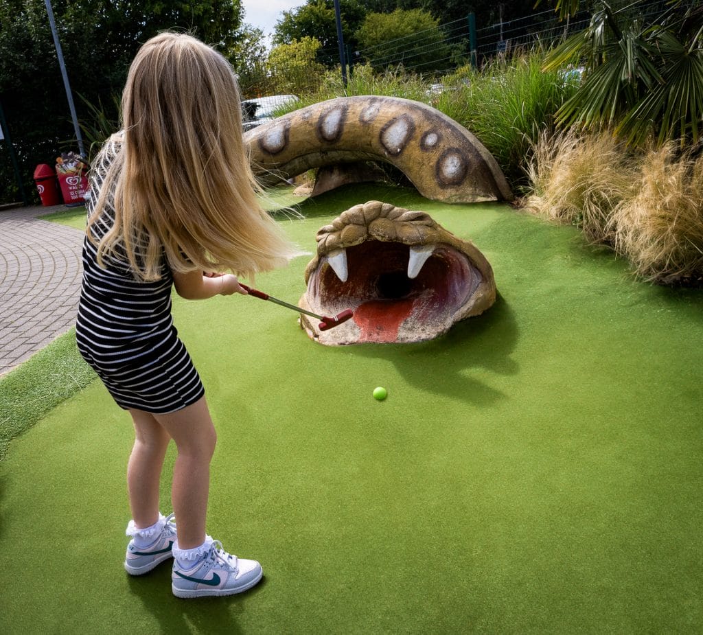 young girl hitting golf ball into snakes mouth at a mini golf course in nottingham