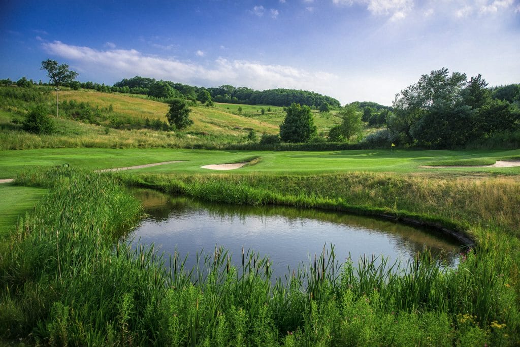 golf green surrounded by bunkers with bright white sand overlooking a pond at one of the best golf courses in nottinghamshire