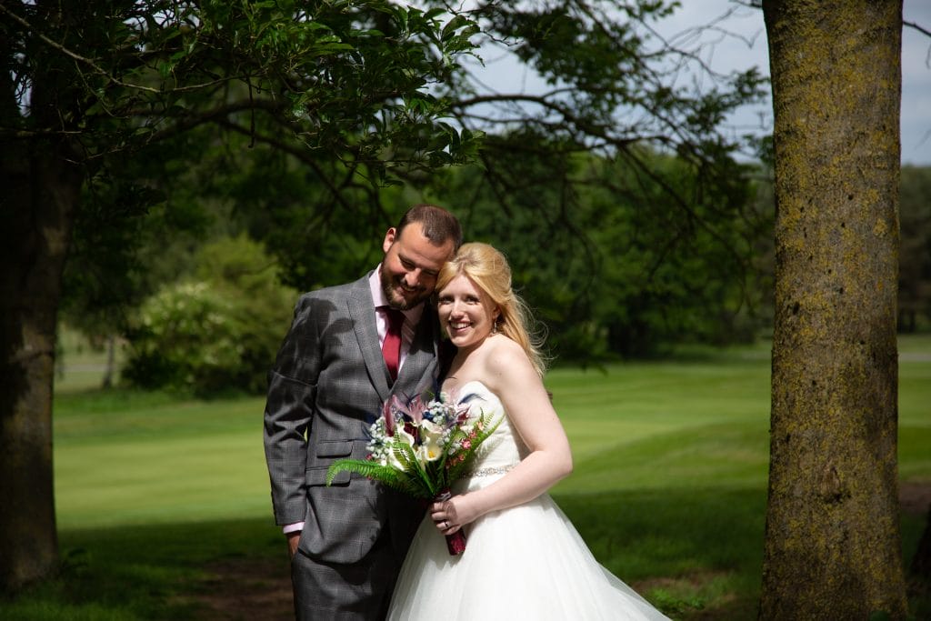 wedding couple posing for photos near trees at a wedding venue in calverton