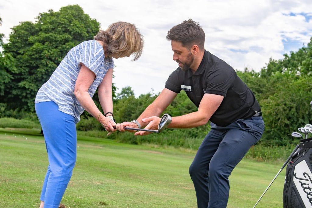 man teaching a women about backswing during a golf lesson in nottingham