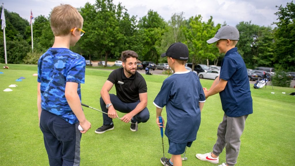 golf coach helping children play golf during a golf lesson in nottingham