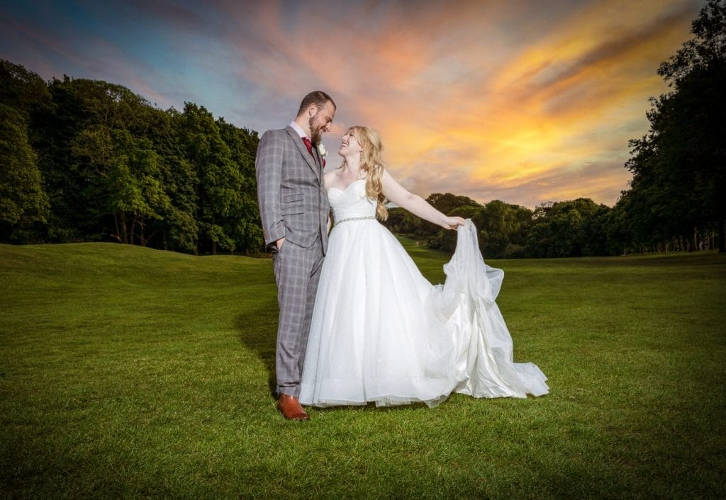 Newly married couple smiling on fairway at Ramsdale Park Golf Club in Calverton with sunset in the background