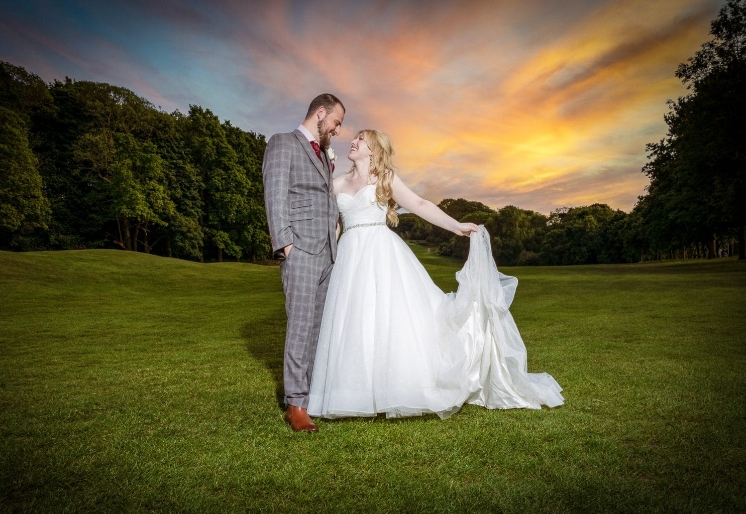 Newly married couple smiling on fairway at Ramsdale Park Golf Club in Calverton with sunset in the background